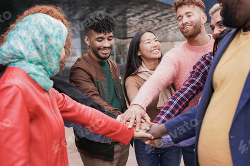 Preview: Group of young multiracial people stacking hands together outdoor