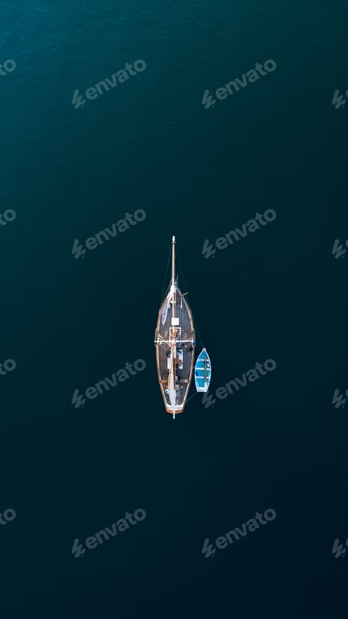 Preview: Top down aerial view of a sail boat sailing towards the light
