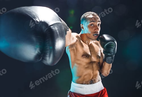 Preview: Determined young man boxing with black boxing gloves