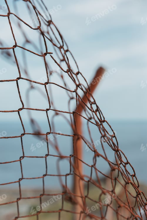 Preview: Closeup shot of an old metal net partition on a beach with sea on the background