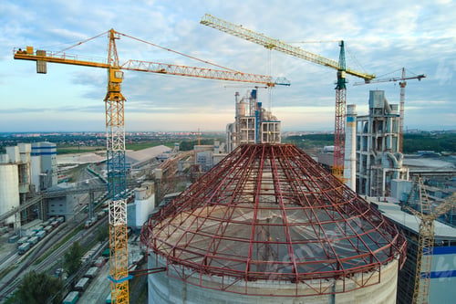 Preview: Aerial view of cement factory under construction with high concrete plant structure and tower cranes