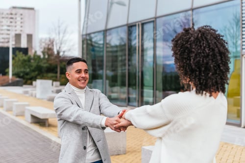 Preview: Shallow focus of a young cheerful couple spinning around near a modern building