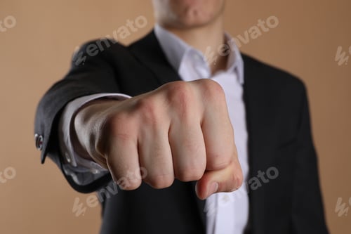 Preview: Businessman showing fist with space for tattoo on beige background, selective focus