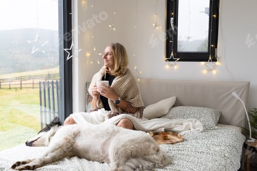 Preview: happy woman with dog relaxing in bed at Christmas time