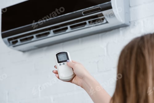 Preview: cropped shot of woman pointing at air conditioner with remote control