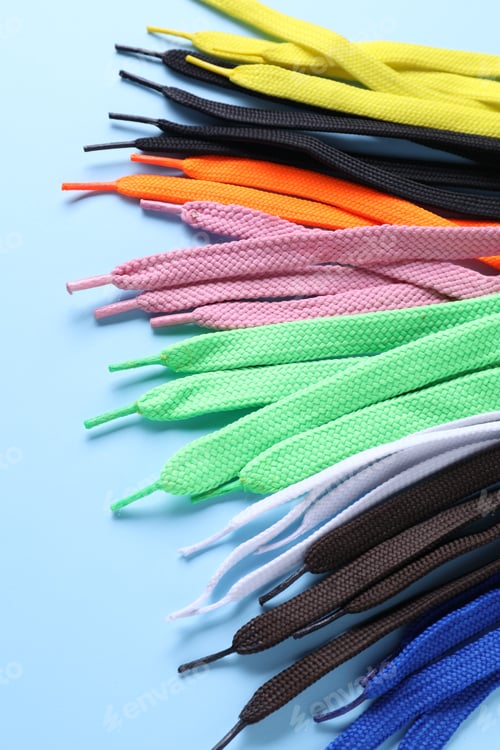 Preview: Many colorful shoe laces on light blue background, above view