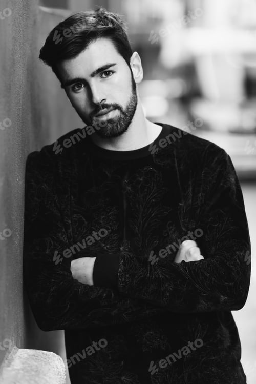 Preview: Young bearded man, model of fashion, in urban background wearing casual clothes.