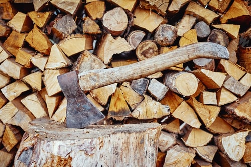 Preview: Close up of axe agains firewood background