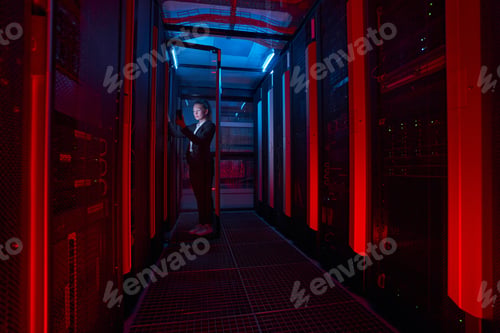 Preview: Female technician working on phone with servers in data center
