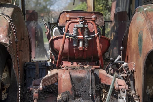 Preview: Rusted old red tractor with blurred trees in the background