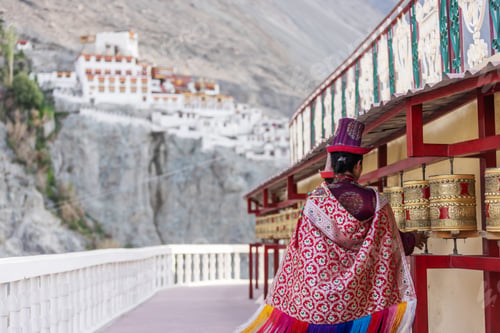 Preview: A traditionally dressed woman walks along a row of prayer wheels at a monastery in Nubra Valley.