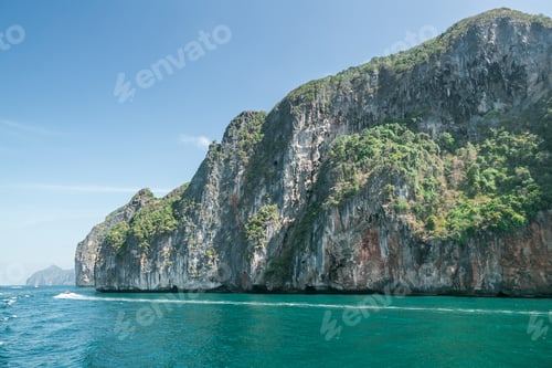 Preview: scenic view of rocky formations covered with green plants, blue sky and ocean in phi phi islands