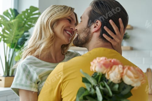 Preview: Handsome young man surprises his girlfriend with bunch of flowers at the kitchen