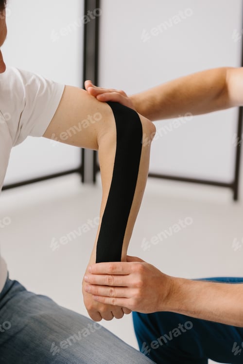 Preview: Close-up of a healthcare professional applying kinesiology tape to a patient's arm.