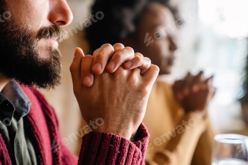 Preview: Young multiethnic couple praying to Lord to bless their food and day