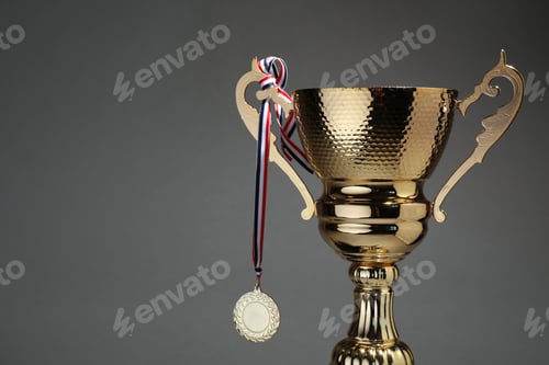 Preview: Golden trophy cup and medal on grey background. Space for text