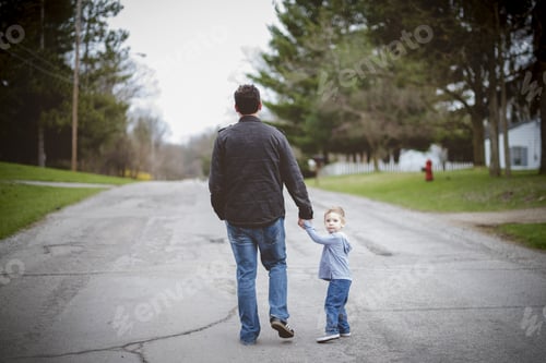 Preview: Father holding his child hand while walking with a blurred background