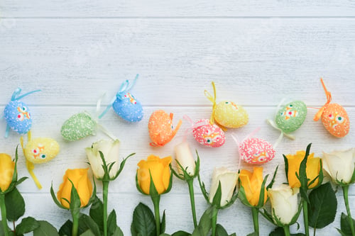 Preview: Happy Easter. Yellow and white roses and colored eggs on white wooden background. Easter background