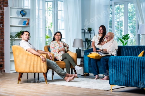 Preview: Portrait of happy Indian family of four sitting in modern living room