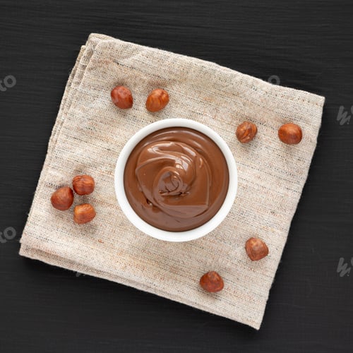 Preview: Homemade Chocolate Hazelnut Spread in a Bowl on a black background, top view.