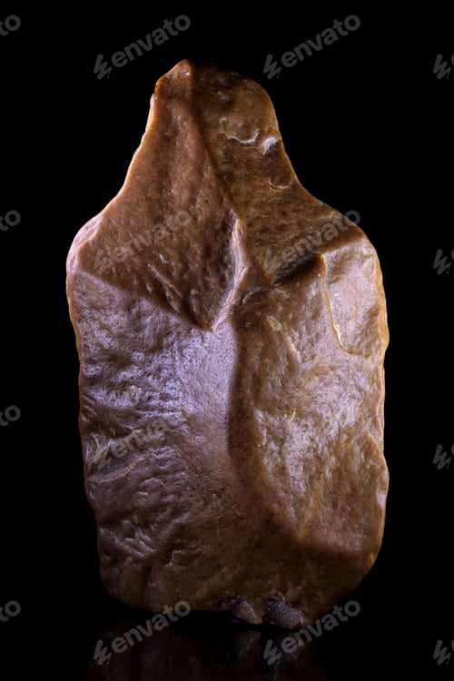 Preview: Vertical closeup shot of an ancient brown stone axehead from the Paleolithic period
