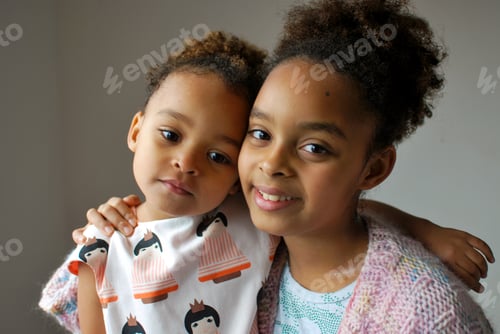 Preview: Portrait of a two sibling girls of mixed race (sisters) wearing a knit sweater - family love