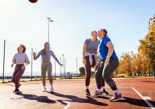 Preview: Diverse group of young woman having fun playing recreational basketball outdoors.