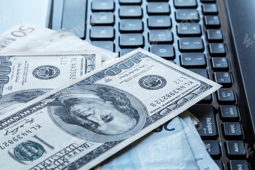 Preview: Banknotes over laptop keyboard