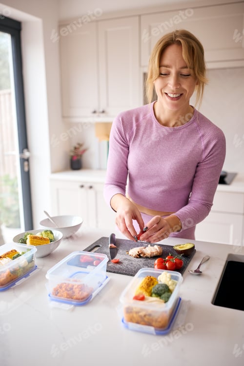 Preview: Woman Wearing Fitness Clothing At Home In Kitchen Making Healthy Meals For The Freezer