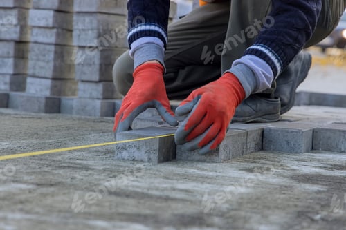 Preview: There is a master laying gray concrete brick slabs on top of foundation base of sand to create a