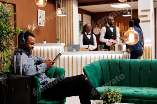 Preview: Man waiting in hotel lobby with tablet