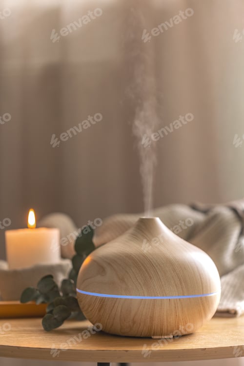 Preview: Modern wooden aroma diffuser releasing mist in cozy home interior. Home relaxation diffuser.