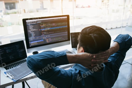 Preview: Asian programmers man are relaxing and looking at the code on the computer screen in the office.