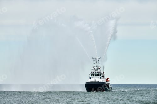Preview: Fireboat ship sails on open sea directing jets of water to sides demonstrating bravery water salute