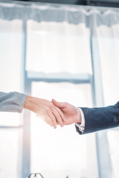 Preview: cropped view of man and woman shaking hands in office