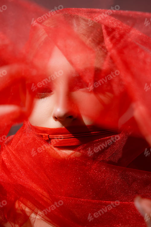 Preview: Young woman with zipper on mouth and blurred red cloth on grey background