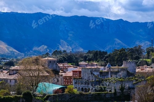 Preview: A view of Llanes, Asturias, showcasing buildings and streets in the foreground, with majestic mounta