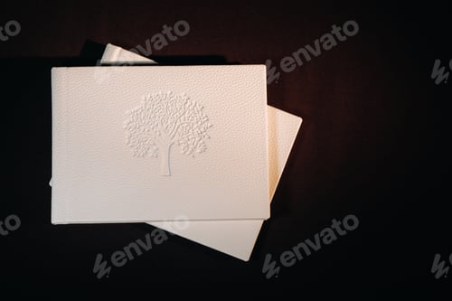 Preview: Composition of photo books in natural white leather of different sizes. The white paper on a dark