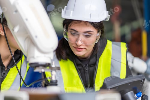 Preview: A team of female engineers meeting to inspect computer-controlled steel welding robots.