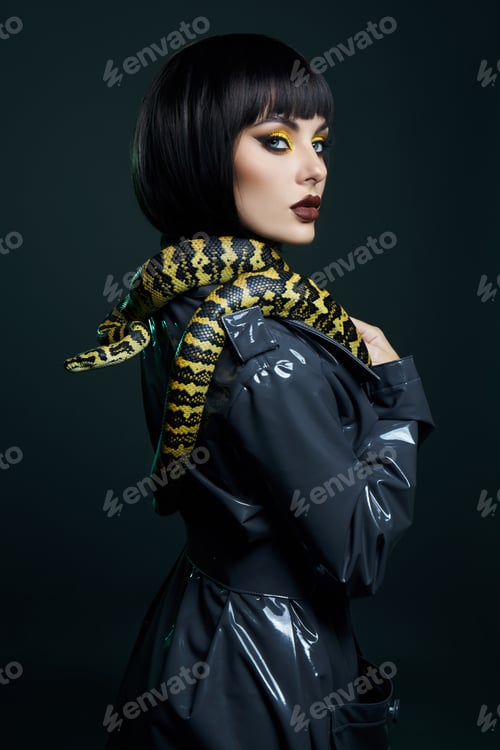 Preview: Beauty woman python yellow snake around her neck on latex shiny raincoat. Yellow snake