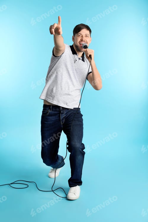 Preview: Handsome man in casual clothes singing with microphone on color background