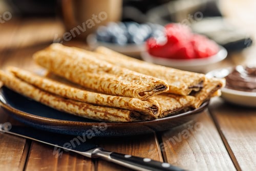 Preview: Freshly Made Golden Crepes Stacked on a Plate, Ready for Breakfast