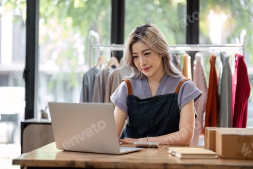 Preview: Portrait of a Asian start-up business owner, looking at camera, working happily with cardboard boxes