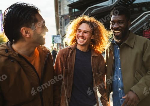 Preview: Three male friends laughing together while walking in the city