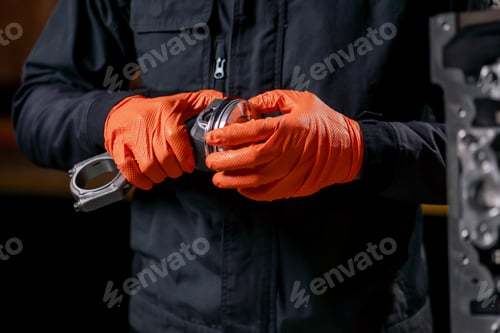 Preview: close-up At a service station on the table young engine repairman assembles a new piston part