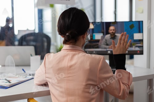 Preview: Businesswoman with face mask greeting remote manager