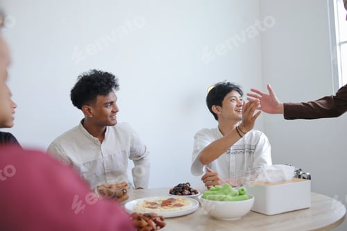 Preview: Muslim Friends Shaking Each Other Hands in Dining Table During Ramadan Celebration