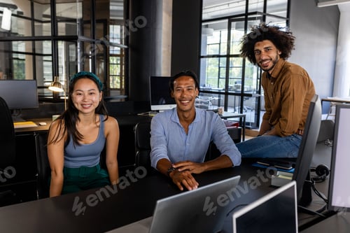 Preview: Smiling business team collaborating at office desk with laptops and documents