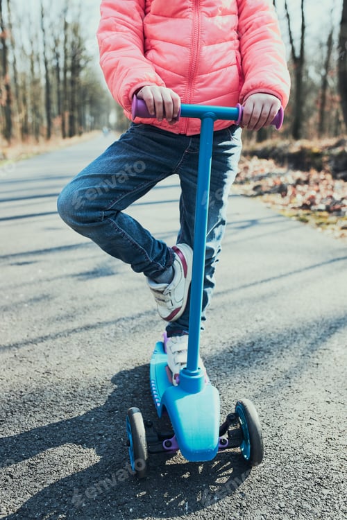 Preview: Little girl playing in the park, riding a scooter, having fun on sunny autumn day