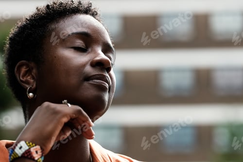 Preview: Head-shot of black woman with eyes closed outside.